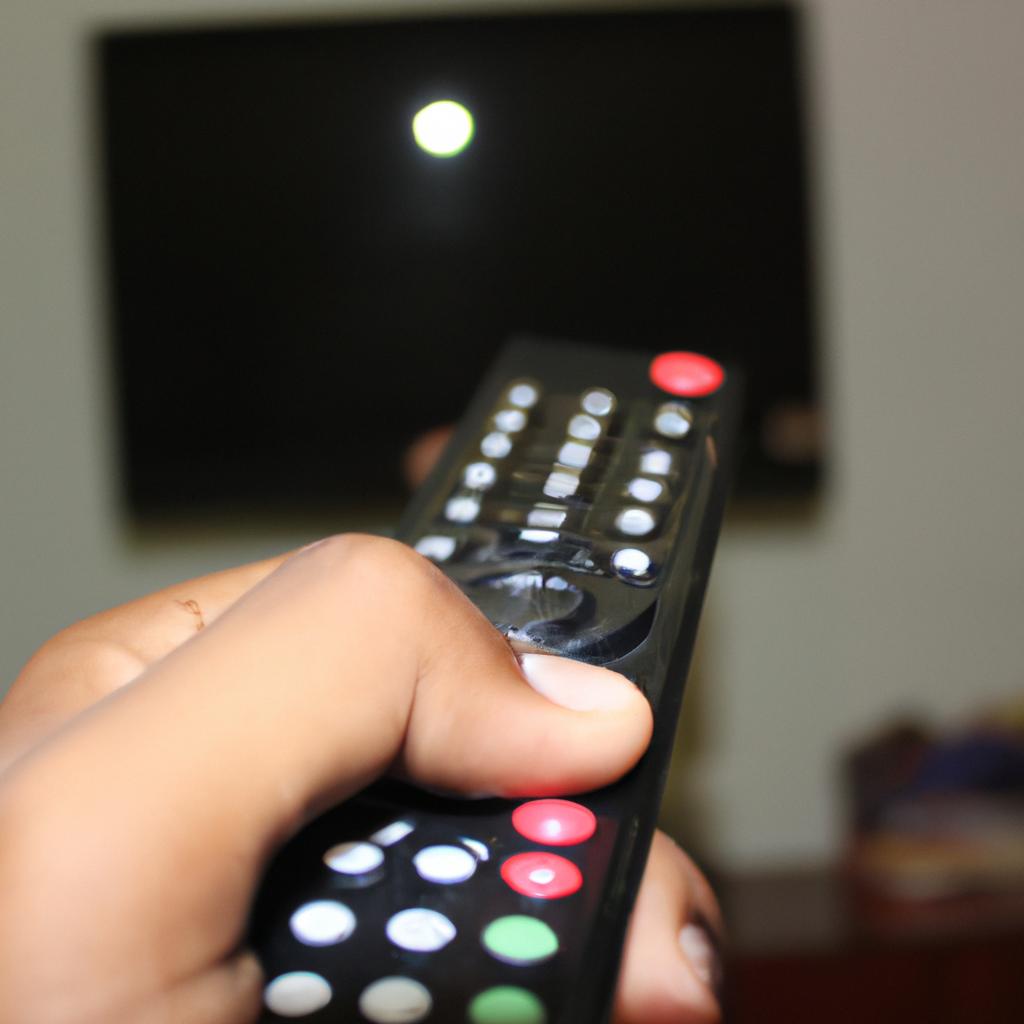 Person holding television remote control
